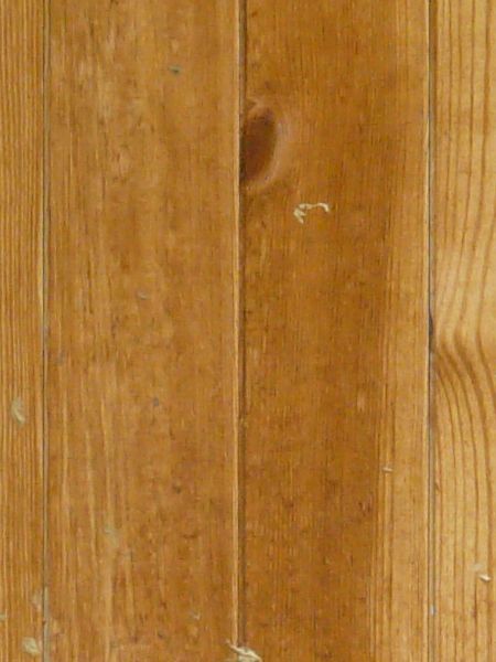 Large wooden door in light brown tone with metal hinges and latch.
